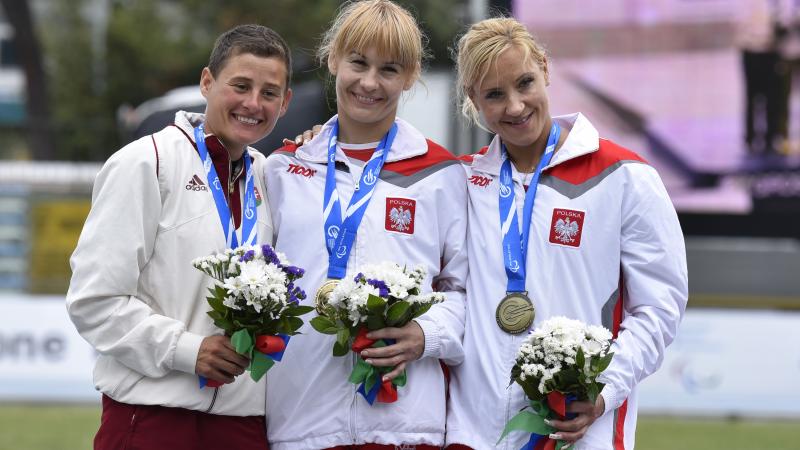 Podium with 3 women holding flowers