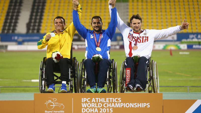 Podium with three men in wheelchairs, celebrating