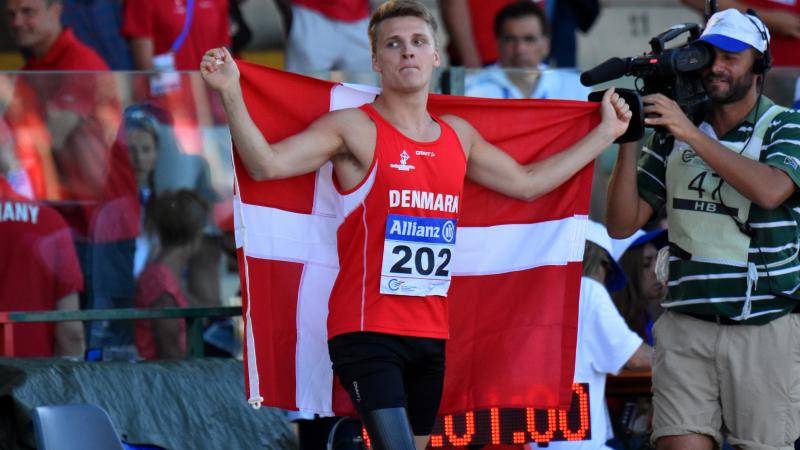 Man in red jersey celebrating with a Danish flag