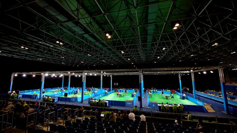 A look inside a venue where table tennis will be contested. On the court are four tennis tables set up.