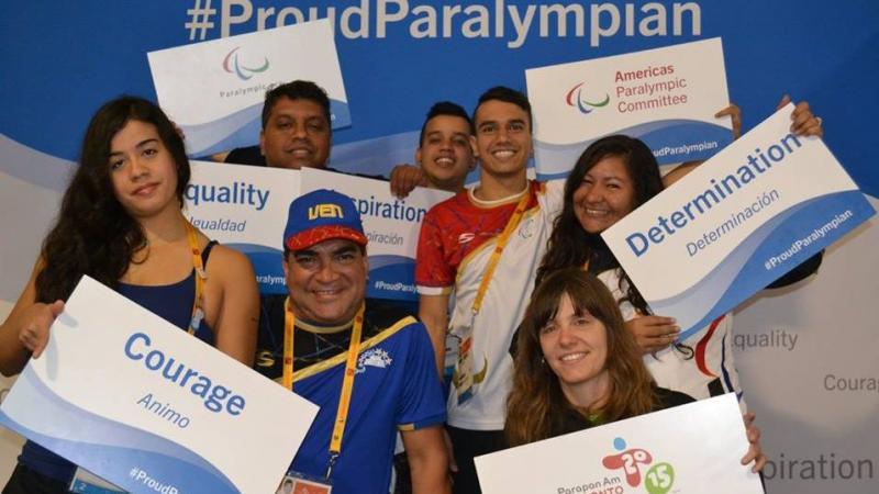 Group picture of four people, smiling and holding signs with 'ProudParalympian'