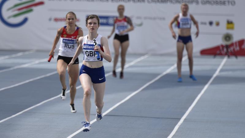 Two women running on a blue track