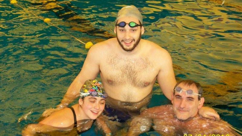 Three people in a pool, smiling to the camera