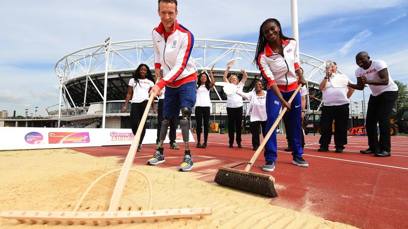 Two athletes cleaning the sand pit