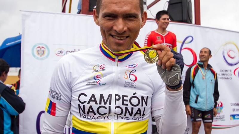 Man with cycling jersey showing his medal, smiling