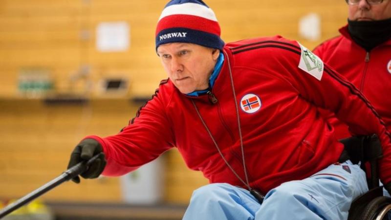 Man in a wheelchair doing curling