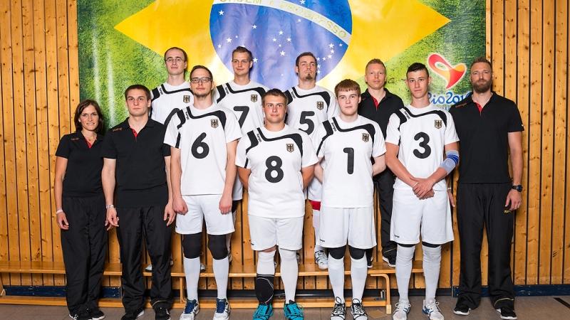 The German goalball team stands in front of a Brazilian flag.