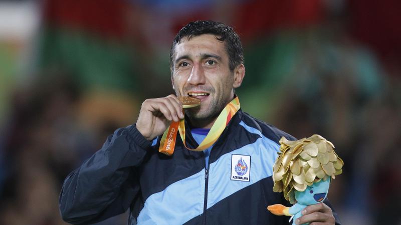 a man bites his medal in celebration