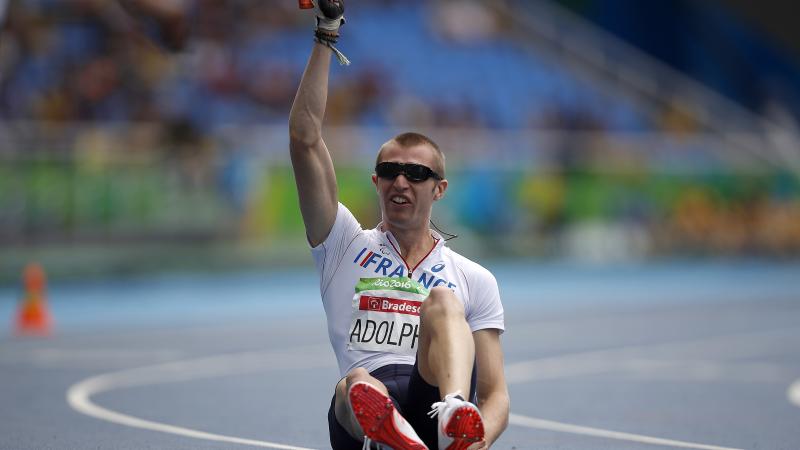 Man sitting on a track raising one arm