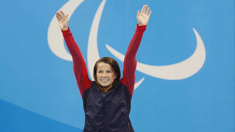 Upper body of a woman, raising her arms in the air