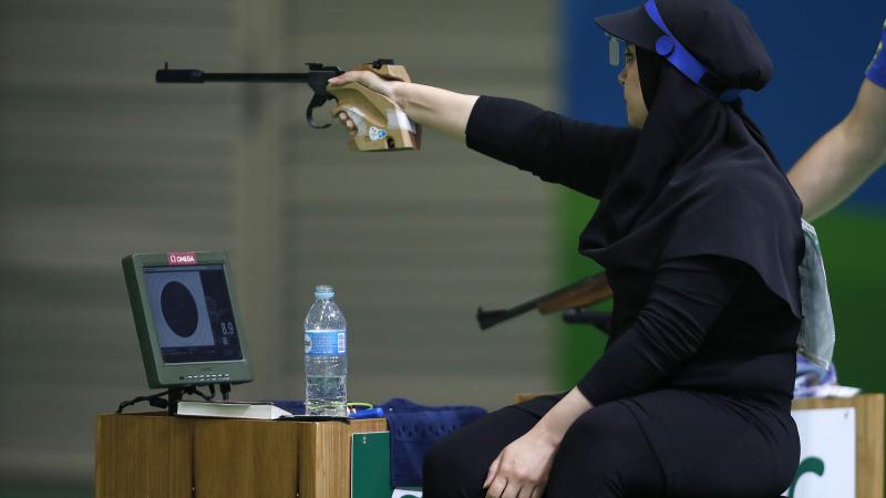 Woman with black headscarf aiming with a weapon