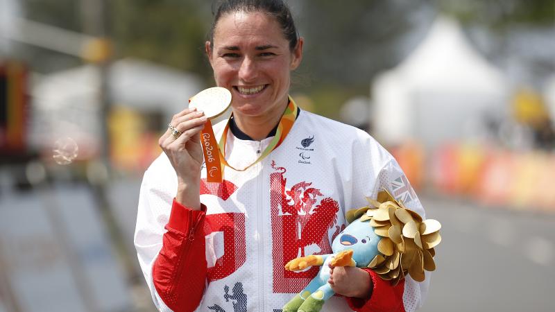 Woman in track suit showing a medal to the camera