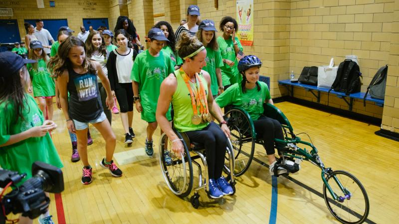 An athletes shows a young girl how to use a racing wheelchair