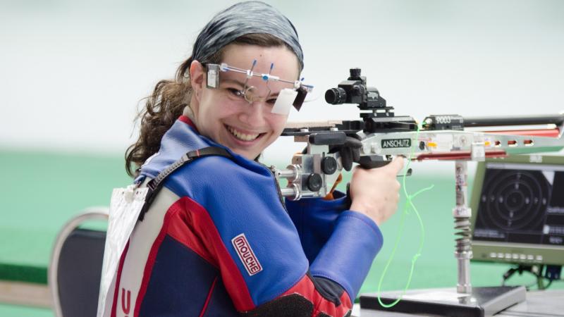 Woman in shooting range, looking back over her shoulder, smiling