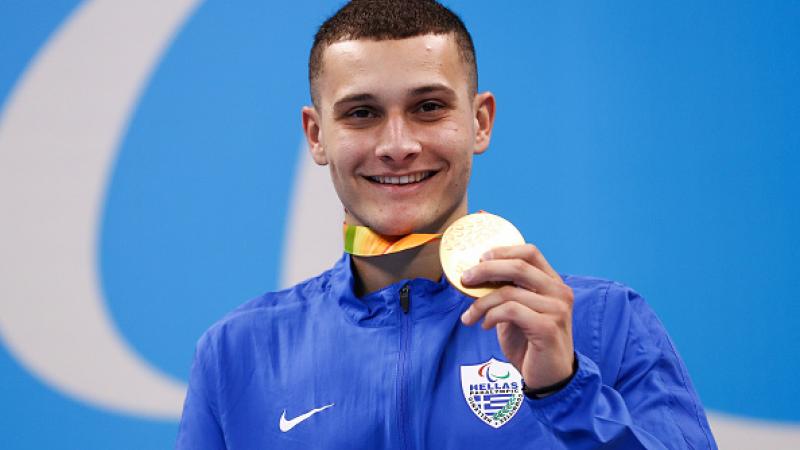 Man on podium showing his medal