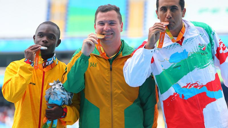 Three men on podium, with their medals