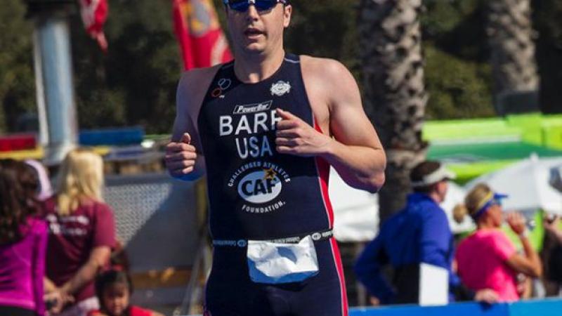 A picture of a man with one prosthesis running and crossing a finish line