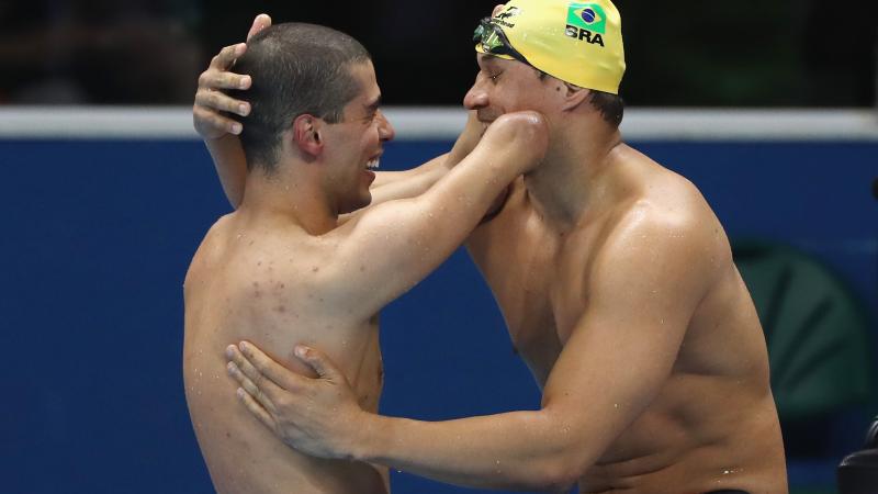 Two Para swimmers embrace after a race