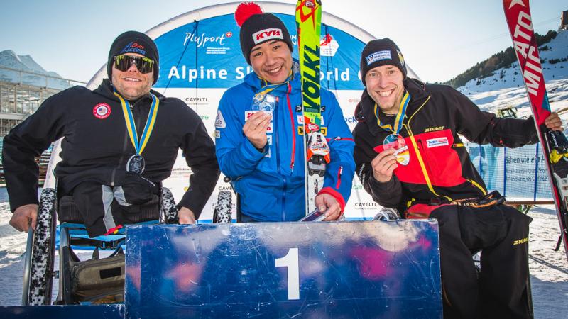 Three sit skiers hold their medals