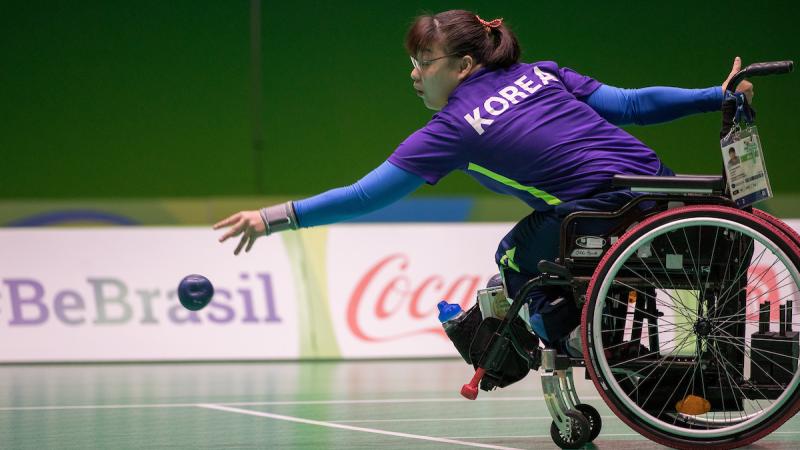 Woman in wheelchair throwing a blue boccia ball