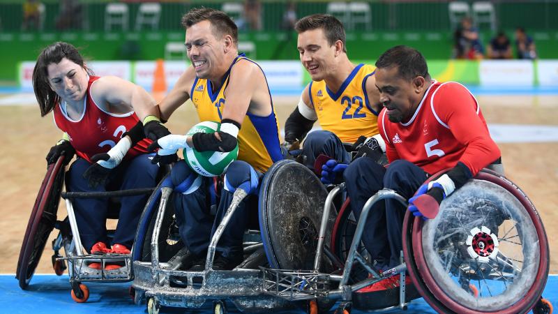 Four wheelchair rugby players fighting for the ball.