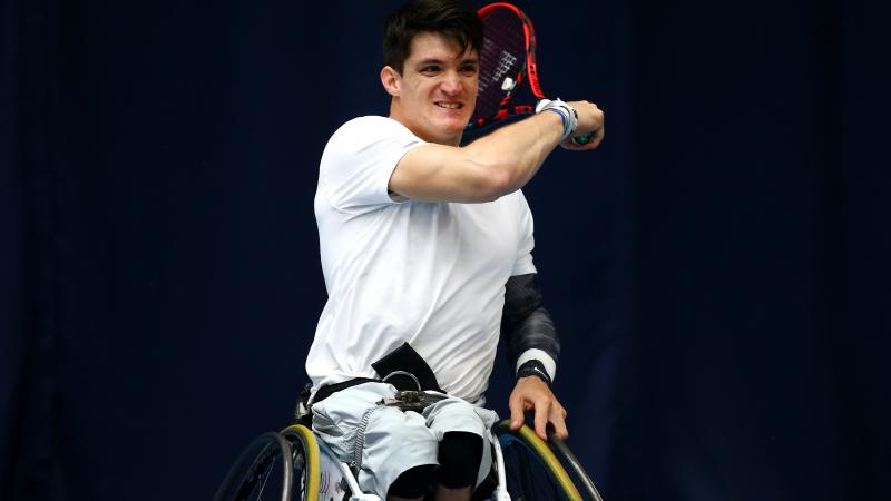 Wheelchair tennis player hits a ball.