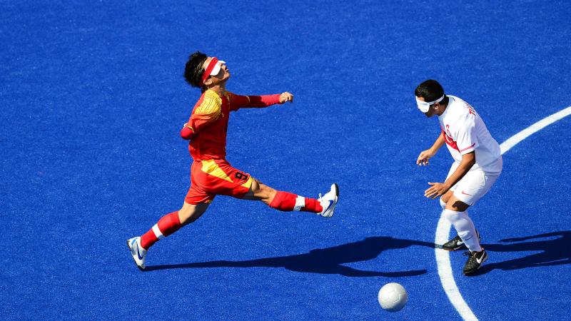 A Chinese blind football player kicks the ball.