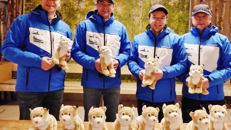 Four men in blue jackets show toys