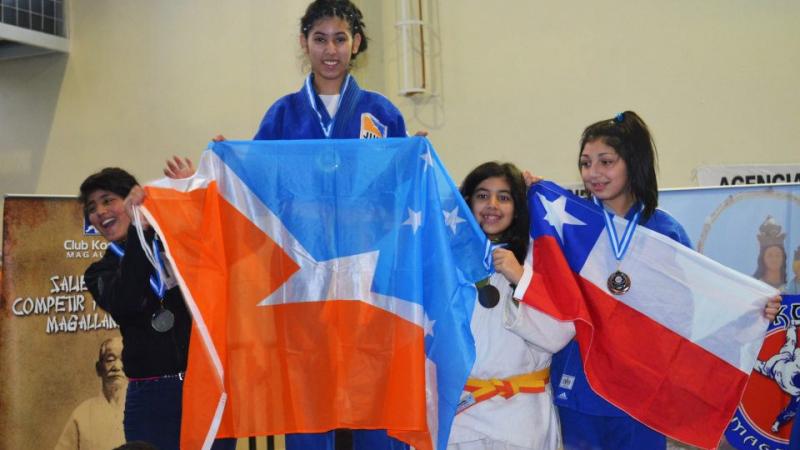 Rocio Ledesma stands on top of the podium whilst holding the flag from her province.