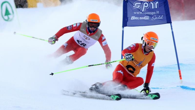 A Para alpine skier and guide make a turn round a gate.