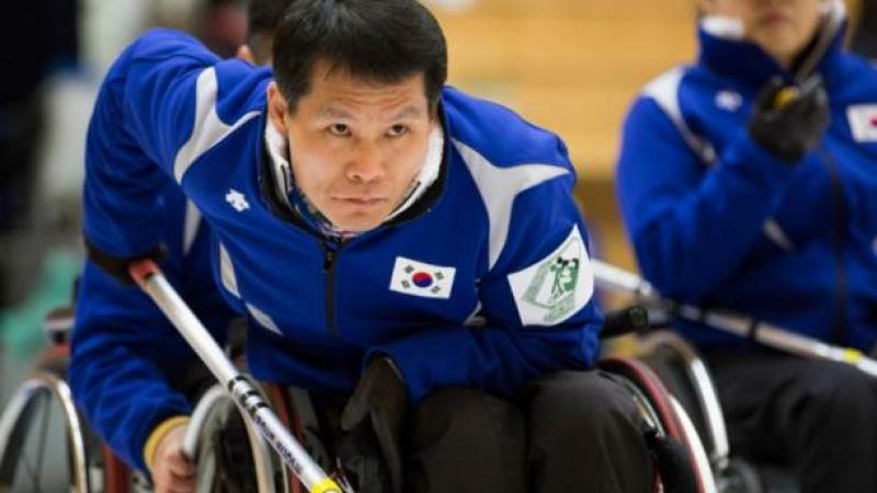 An athlete in a wheelchair competing in a game of curling. 