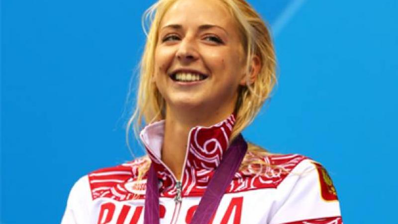 A picture of a woman standing with a silver medal around her neck