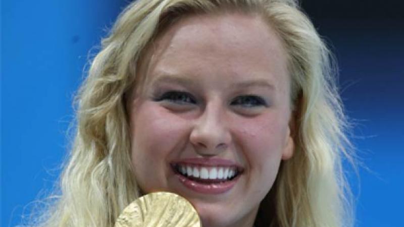 A portrait of a blond woman showing her gold medal