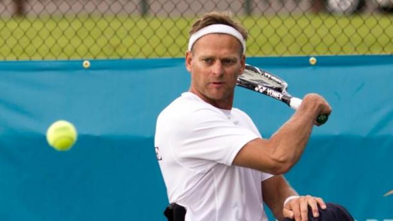 A picture of a man in a wheelchair playing a backhand