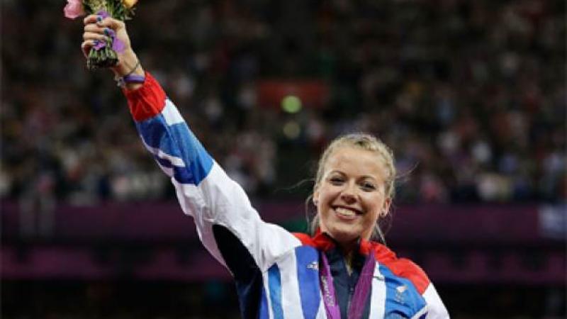 A picture of a woman showing her gold medal during a medal ceremony