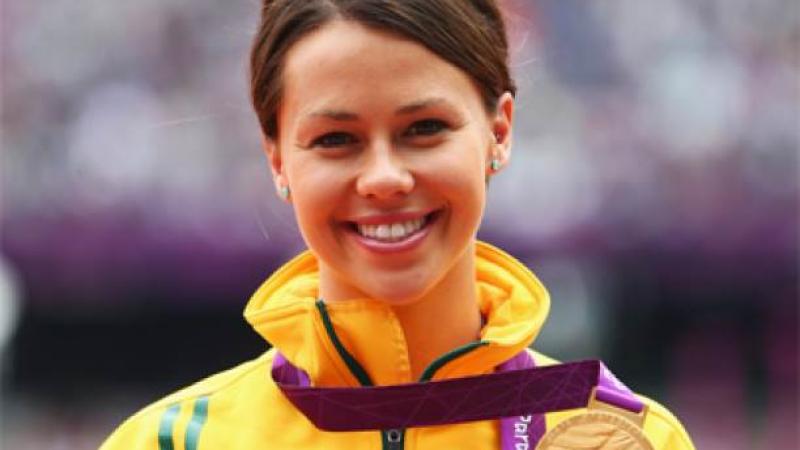 A picture of a woman showing her gold medal hanging around her neck