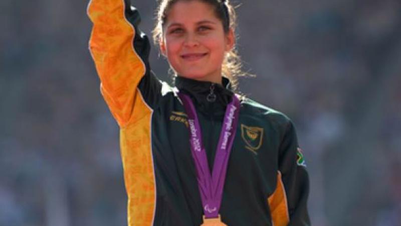 A picture of a woman with a gold medal around her neck during a medal ceremony.