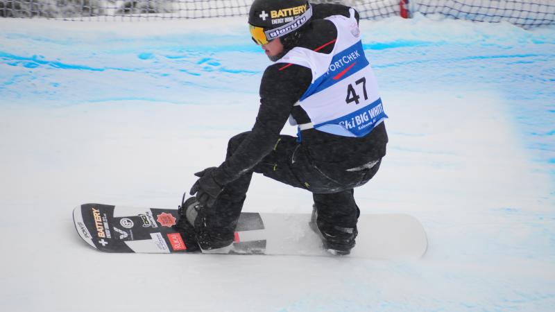 Man on snowboard rides down a snowboard-cross course.