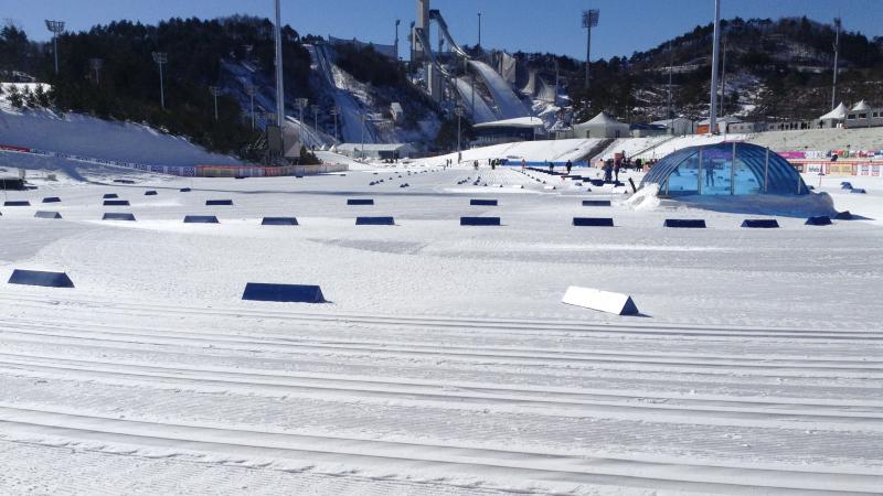 View on a snowy cross-country venue with a ski jump in the background