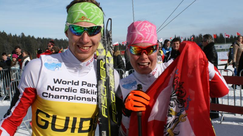 Two cross-country skiers with an Austrian flag