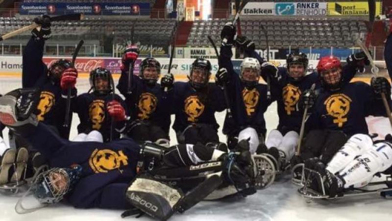Group of female sledge hockey players pose for a photo