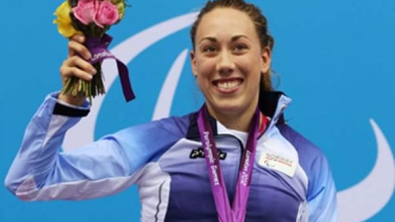 A picture of a woman in a wheelchair showing her gold hanging around her neck