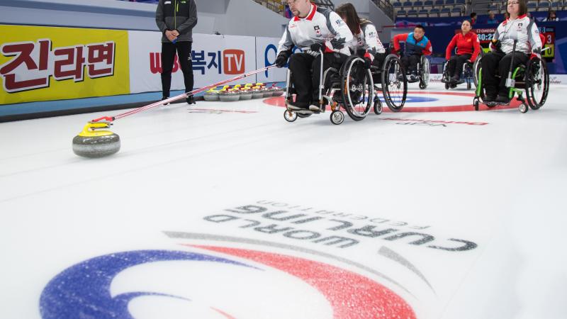People in wheelchairs on ice rink, curling