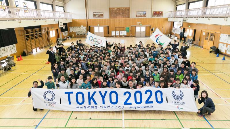 Group picture of many people gathering around a banner