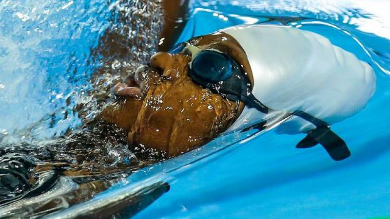 Athlete in water with goggles competes in backstroke 