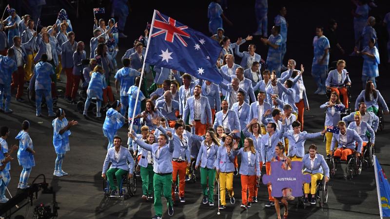 A group of Para athletes march into a stadium with one athlete holding the Australian flag during the Rio 2016 Opening Ceremony