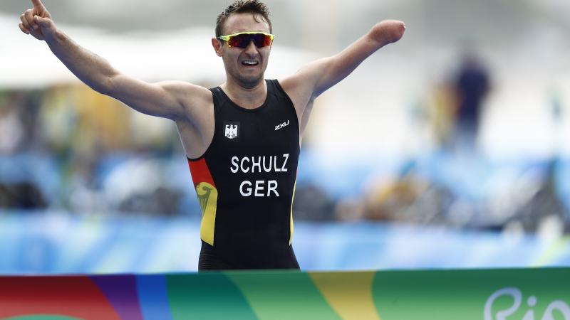 Man with missing left forearm races arms as he is about to cross a finish line