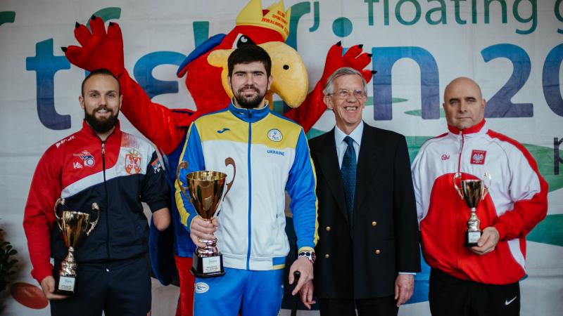 Three men holding trophies 