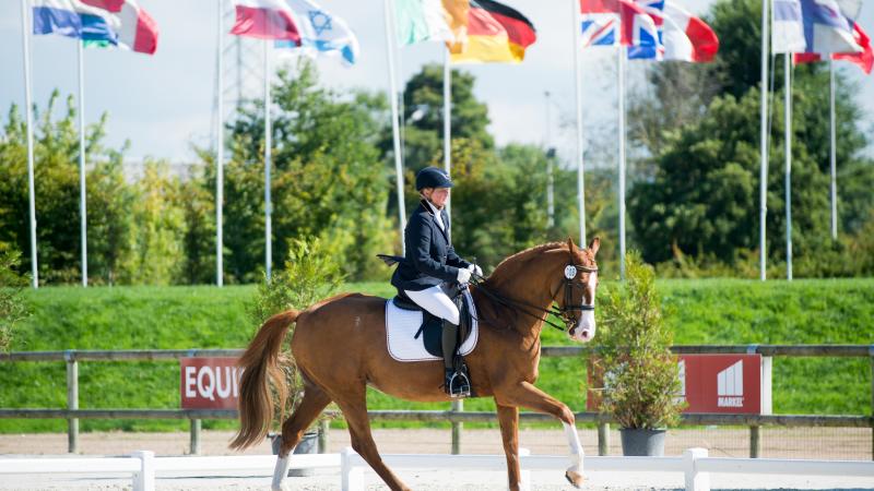 Woman riding a horse with various nation's flags in the background