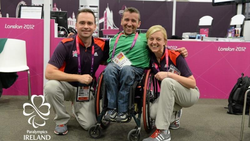 Man in wheelchair between two people posing for photo